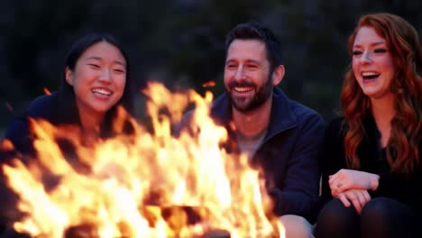 a joyful gathering around the campfire: friends engaged in laughter and storytelling amidst a warm blaze of flickering flames
