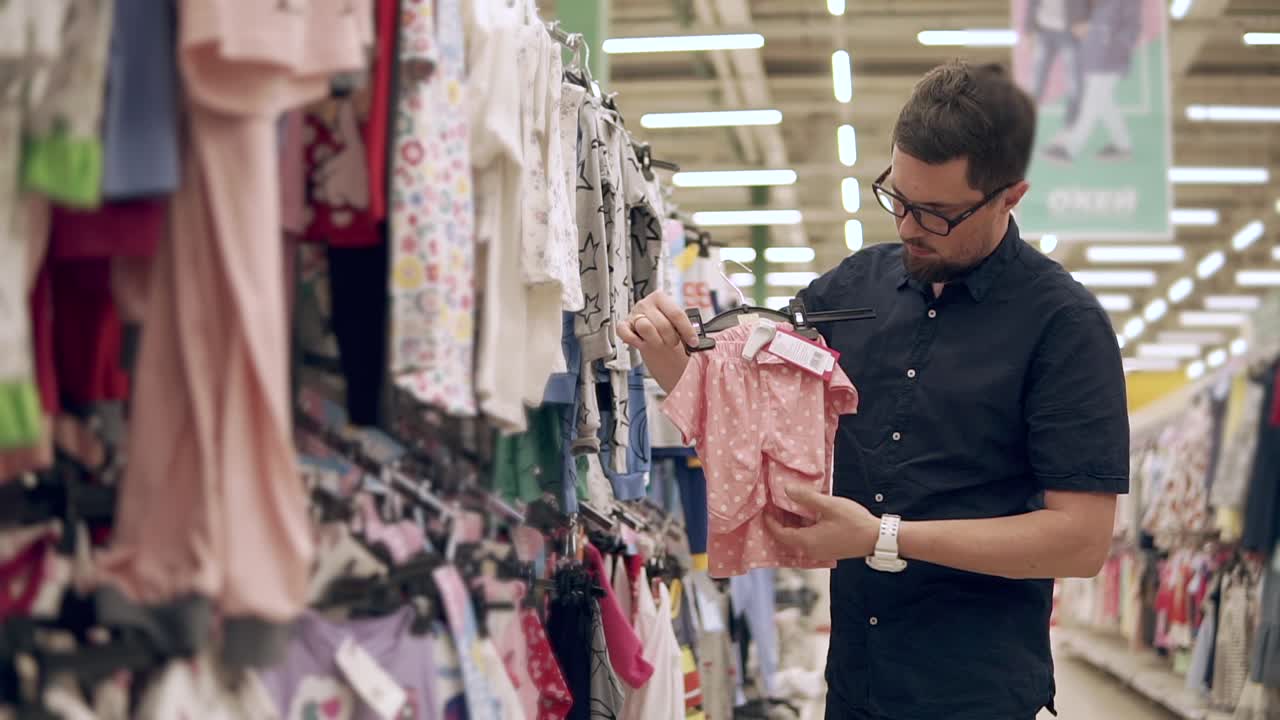 Uomo che acquista vestiti per bambini in un negozio al dettaglio