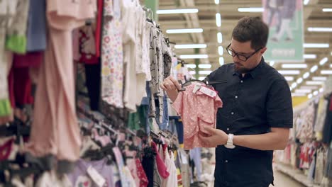 hombre comprando ropa para niños en una tienda minorista