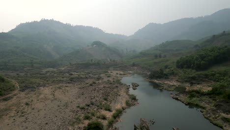 valle de montaña brumosa con un río