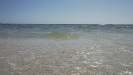 looking out to sea on a beautiful sunny day as the waves gently wash in along the shore of the fine gravelly beach.