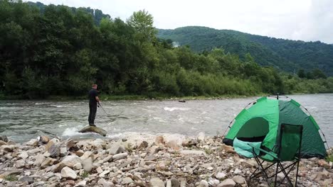 a beautiful mountain river a tent and a tourist who fishes for dinner a beautiful mountain river a tent and a tourist who fishes for dinner budget vacation in the mountains fisherman concept