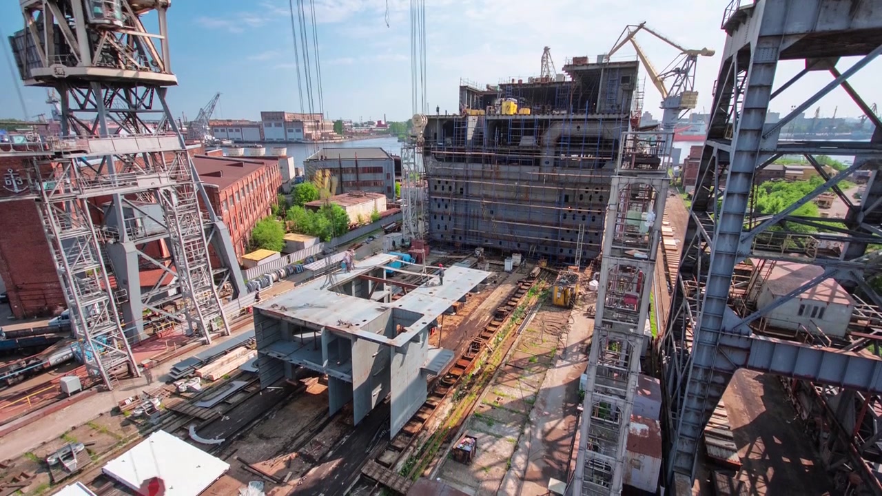 The construction of a large ship on a shipyard with cranes timelapse from above. A fragment of the case in the workshop of the plant. Metal frame during assembly