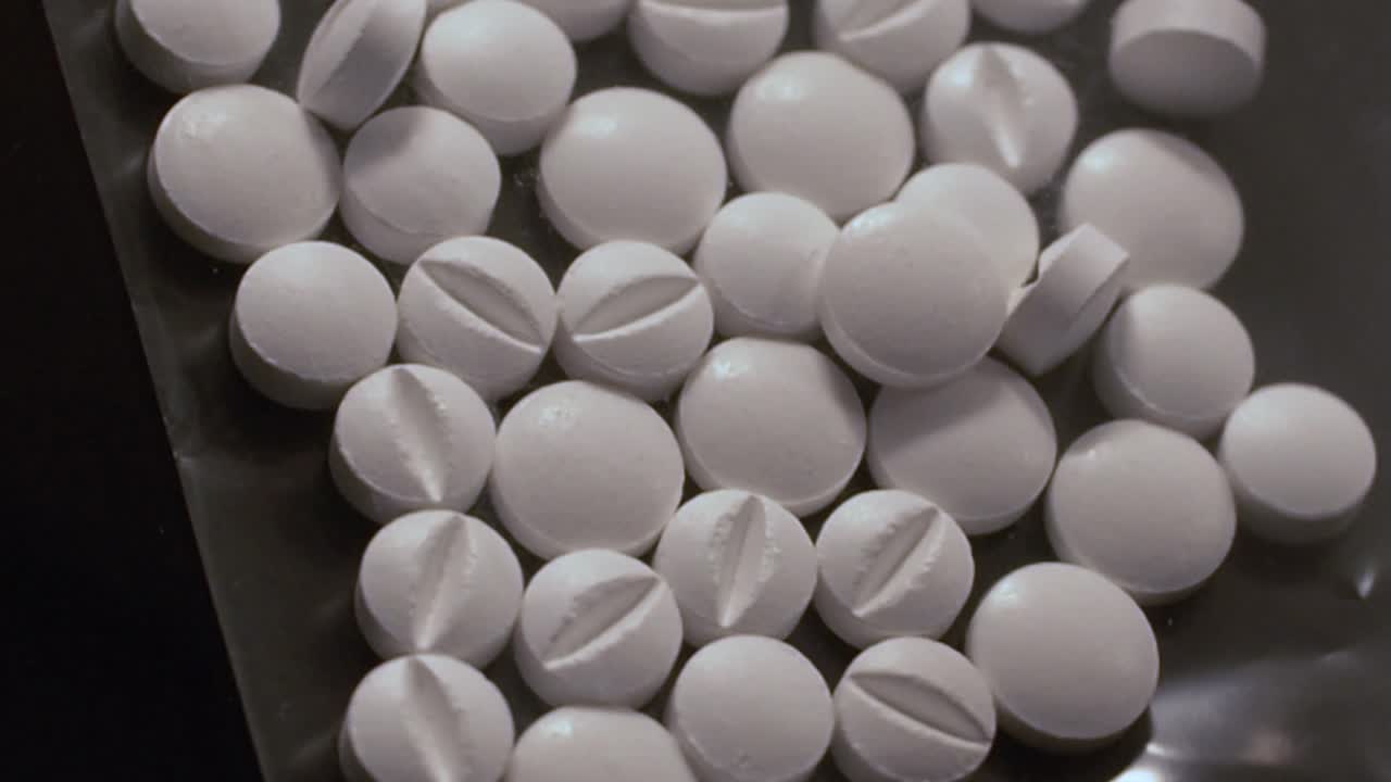 검은 장갑을 쓴 손이  알약이 들어있는 플라스틱 봉투를 만지는 오피오이드 위기