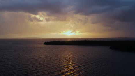 drone flying over a lake at sunset under a stormy sky