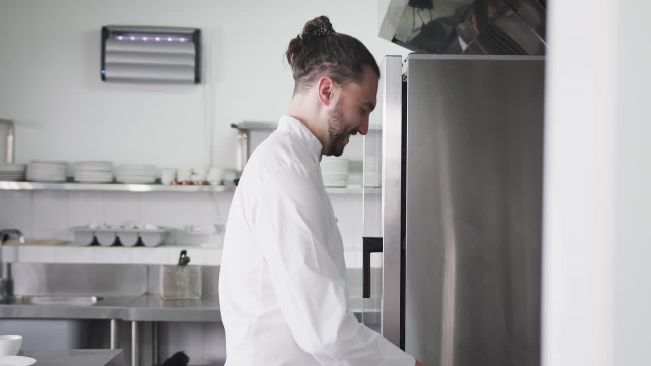 Chef maschio caucasico felice con chignon che lavora nella cucina di un ristorante, spazio per il testo, slow motion