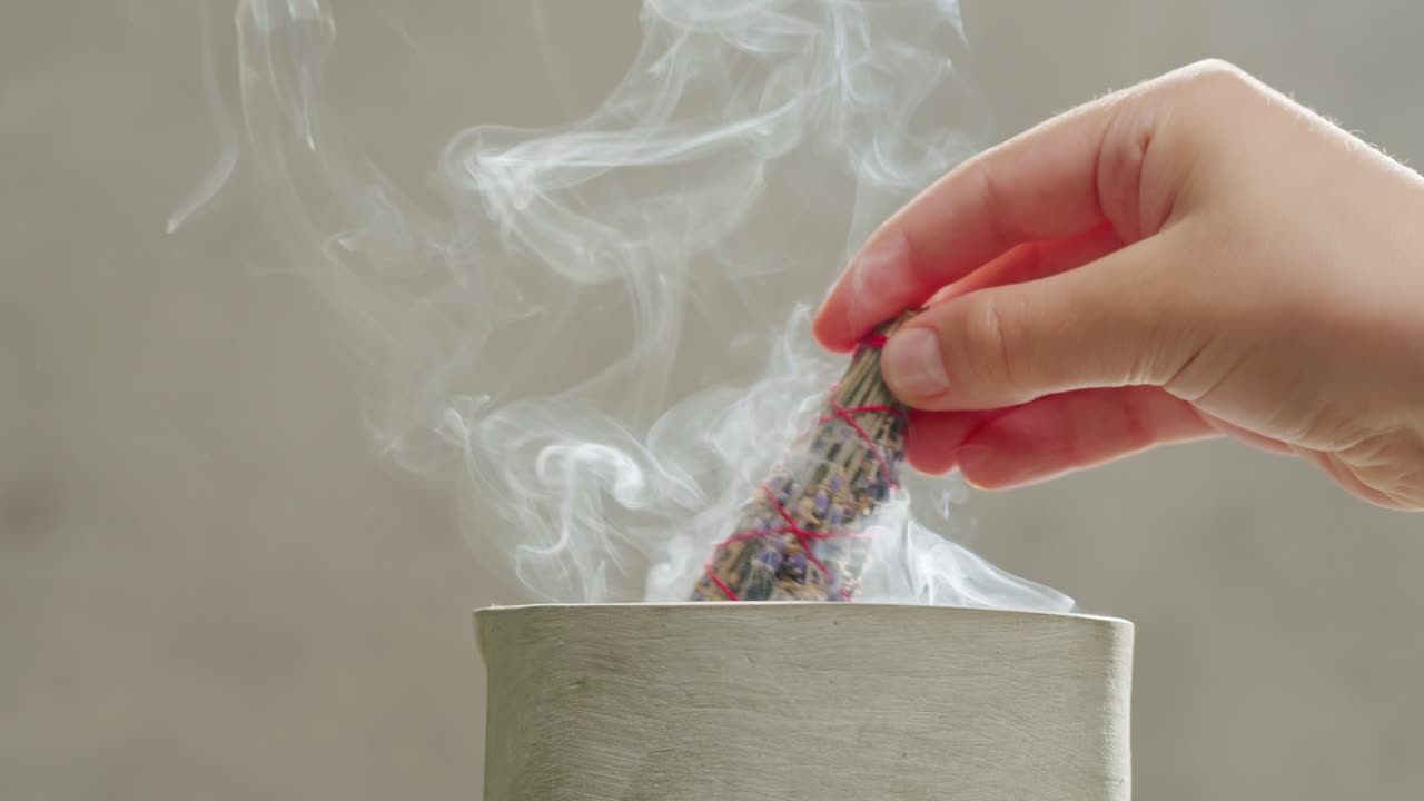 Person holding Palo Santo wood stick in hand, aromatic Palo Santo burning on black background, smoke spreading around, slow motion video clip, high quality 4k close up footage. High quality 4k footage