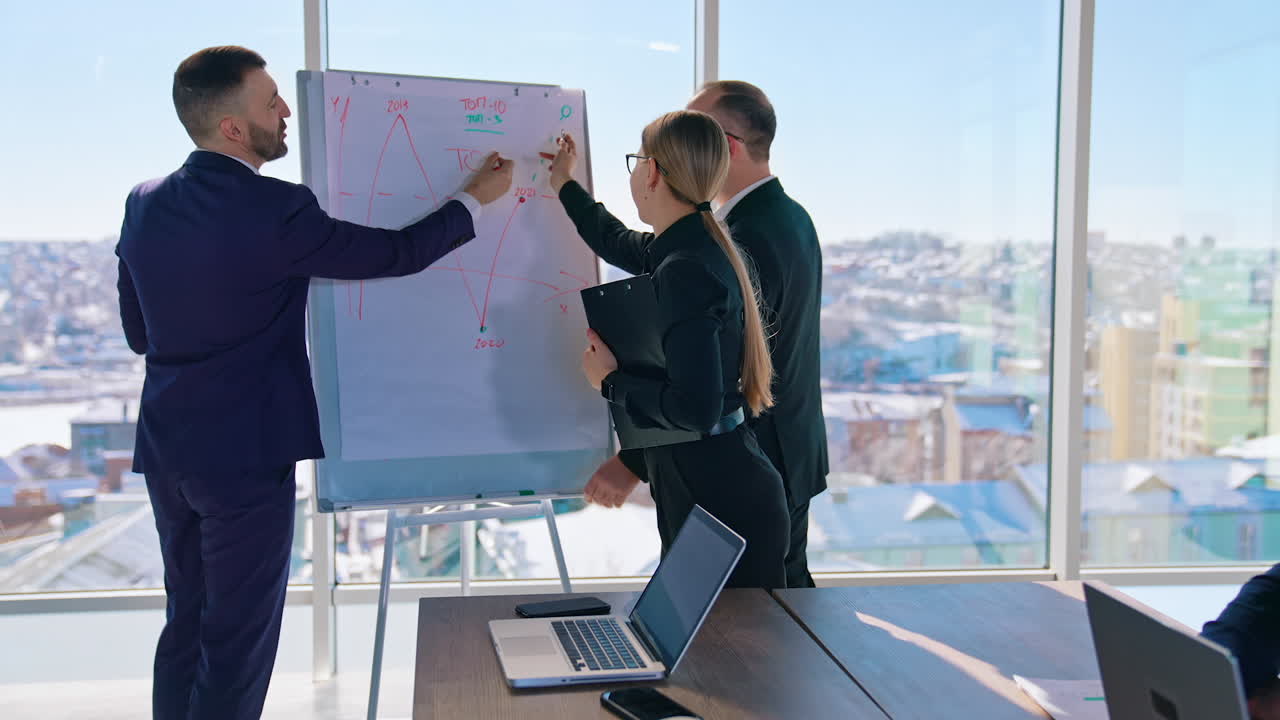 Cheerful business people talk in office. Teamwork of managers planning new strategy. Group of entrepreneurs talking about business near the board with graphs.