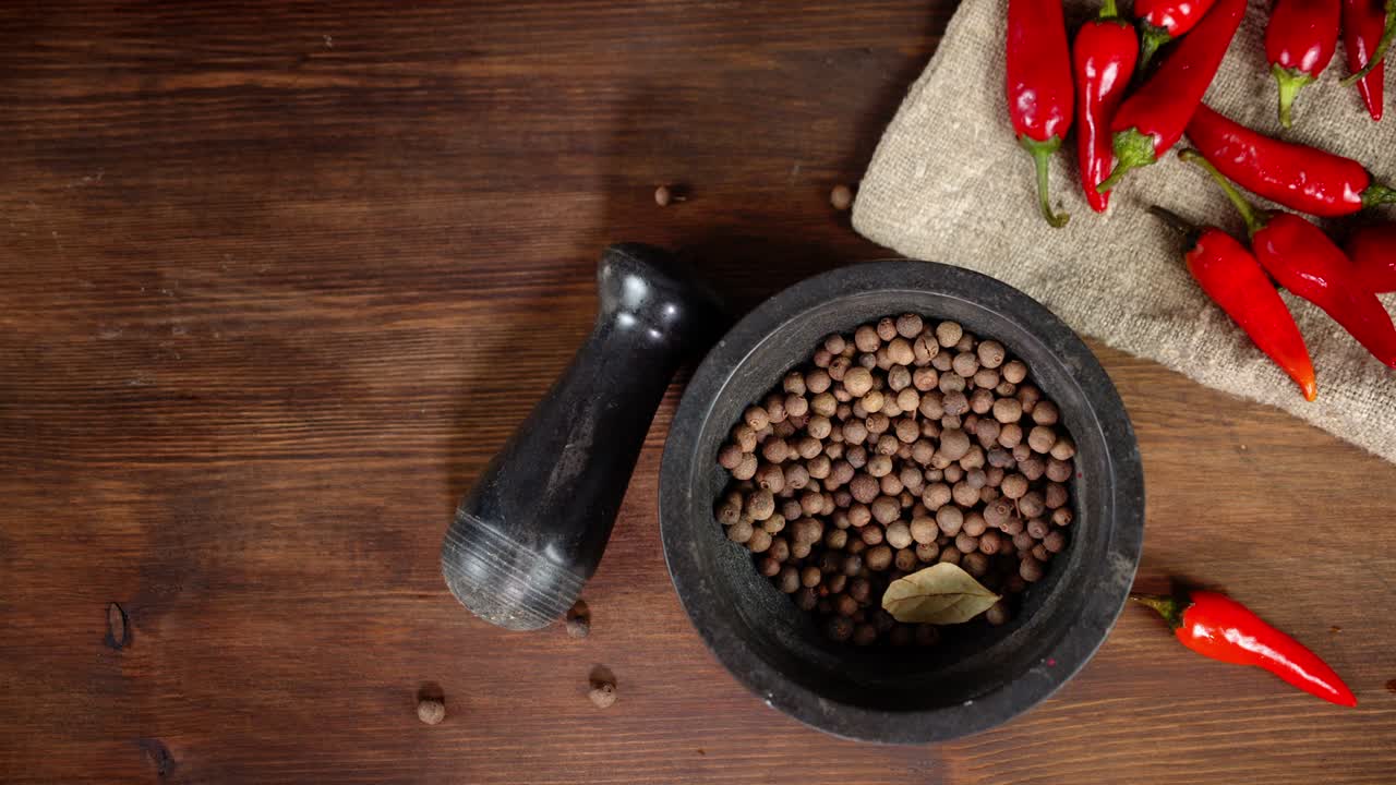 pimienta negra en un mortero con pimienta roja en la bolsa.