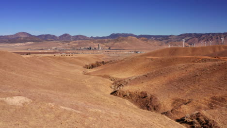 arid grassland, hills, mountains, rural farming land and wind turbines in the mojave desert and tehachapi area of southern california