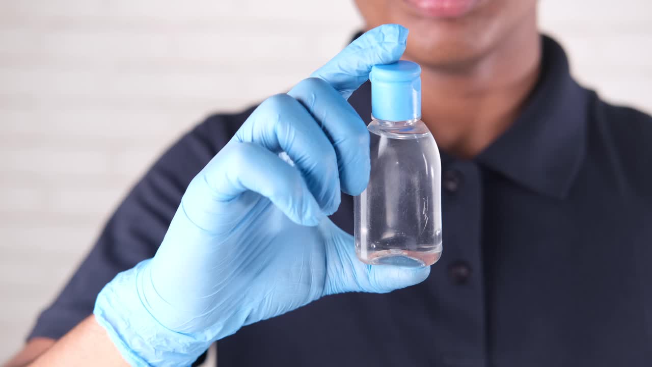 persona con una botella de desinfectante de manos con guantes azules
