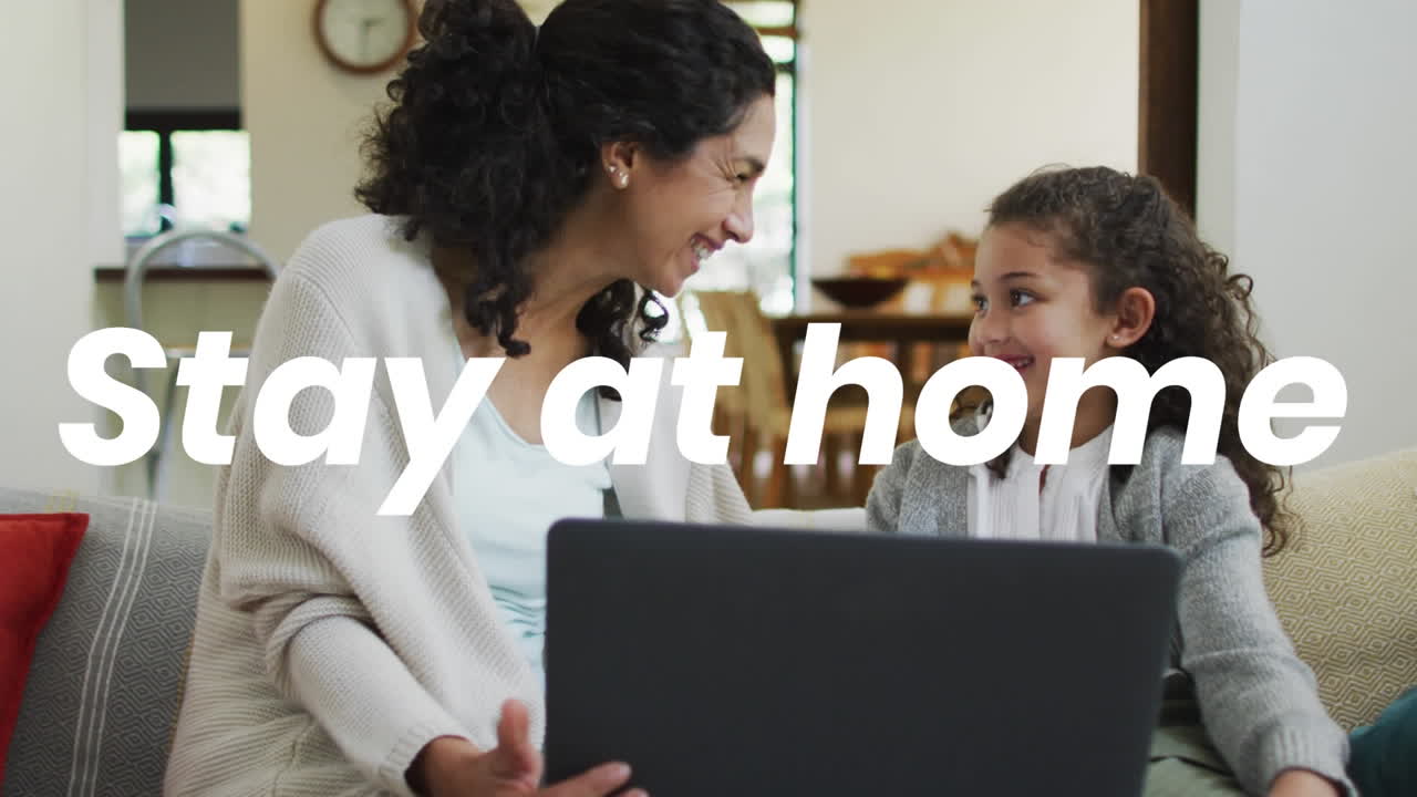 Animation of stay at home text over biracial mother and daughter using laptop