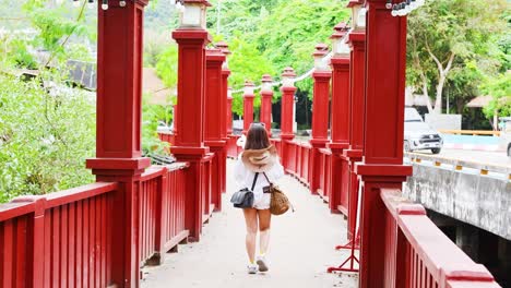 woman strolls along vibrant red bridge path