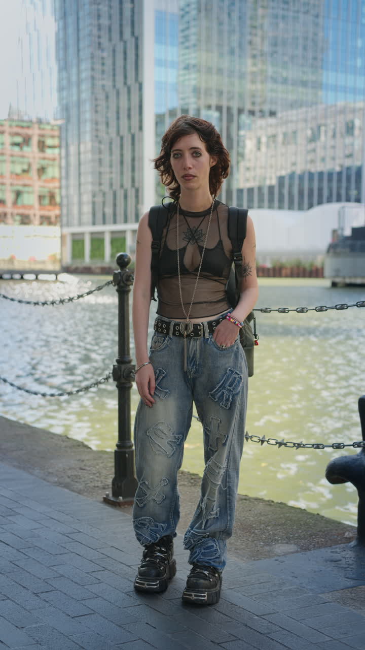 retrato vertical de moda al aire libre de una mujer joven de estilo alternativo con tatuajes y piercings en canary wharf en los muelles de londres filmado en tiempo real