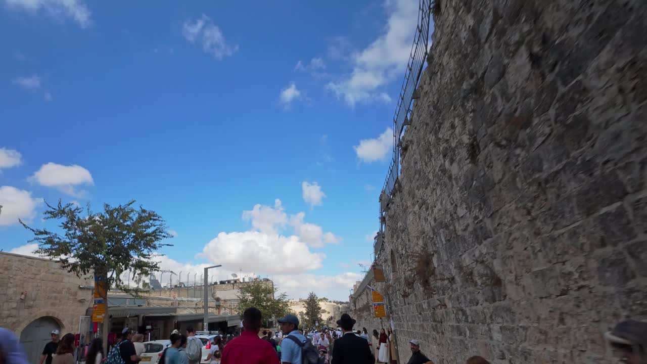 Hyperlapse of a crowded street walking alongside the ancient walls of Jerusalem's Old City, Israel