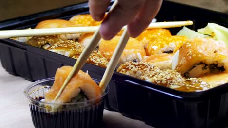 palillos que toman un rollo de sushi y lo sumergen en salsa de soja