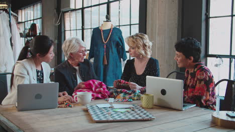 four fashion designers in meeting discussing garment