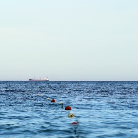 blue sea water. save swimming zone marked by buoys on sea. ship sailing on the water far away.