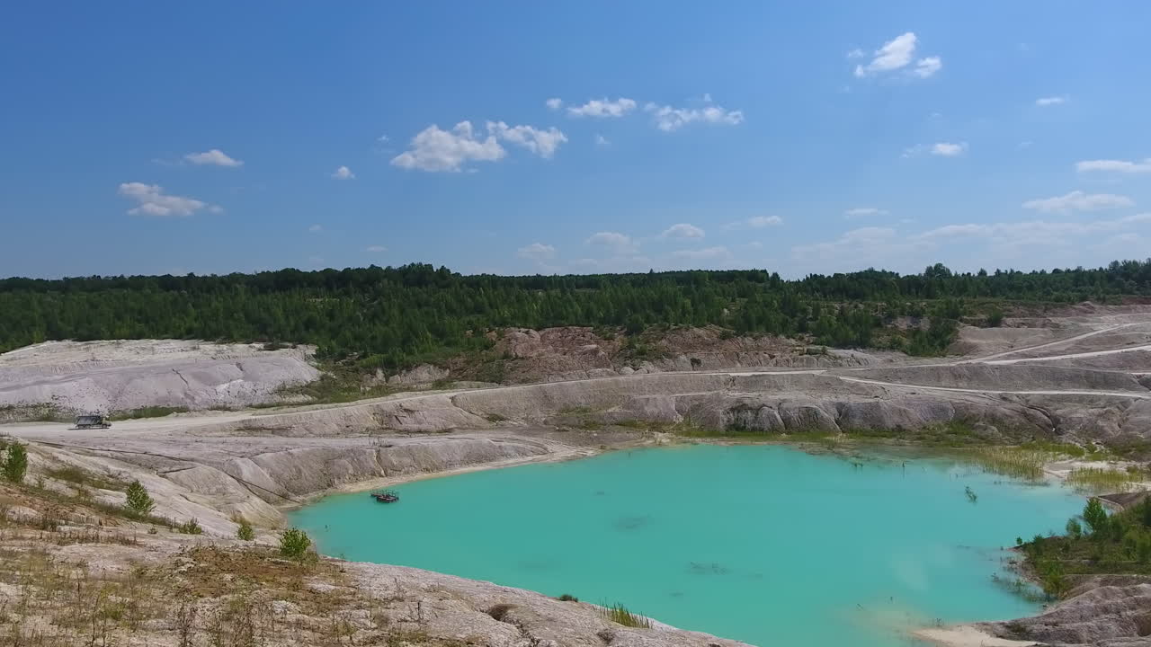 Beautiful landscape of kaolin quarry. Deep clay mine filled with water. Blue sky reflecting in the pond.