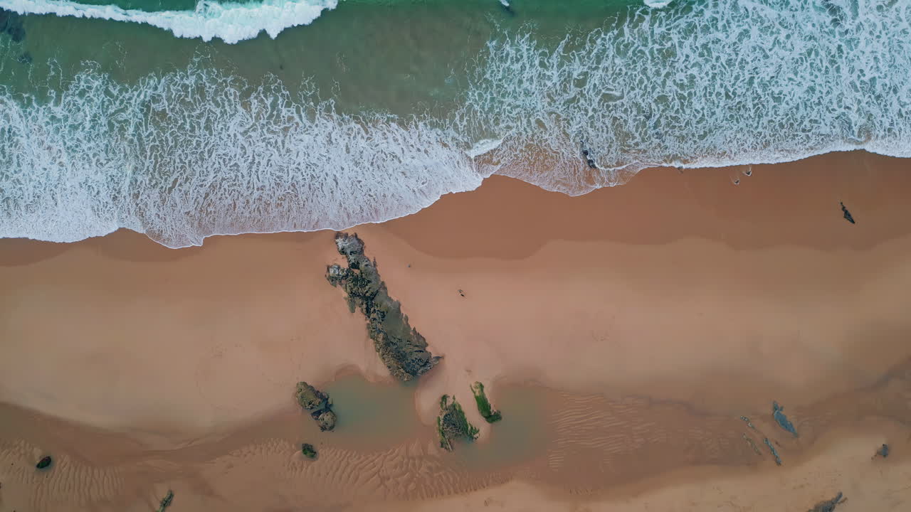 Foaming waves washing beach in aerial view. Turquoise ocean carving textures