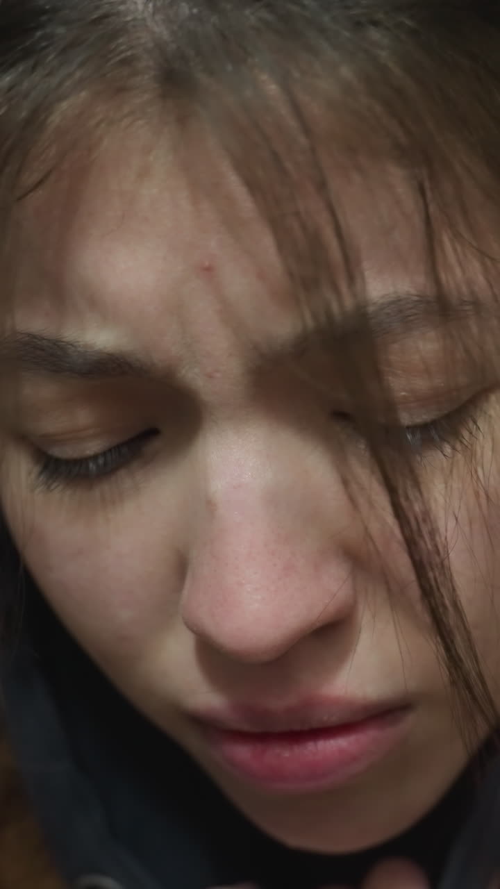 지하 통로에 서있는 무거운 마음의 소녀의 클로즈업 : 그녀는 깊이 불행해 보이며, 고통스러운 표정으로, 그녀의 손은 부분적으로 그녀의 얼굴을 고, 감정적 혼란을 전달합니다.