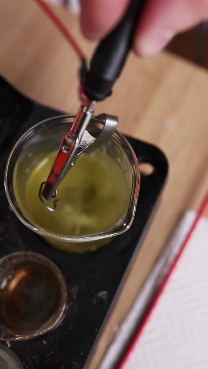 Gioielliere che immerge un anello in una soluzione detergente chimica.