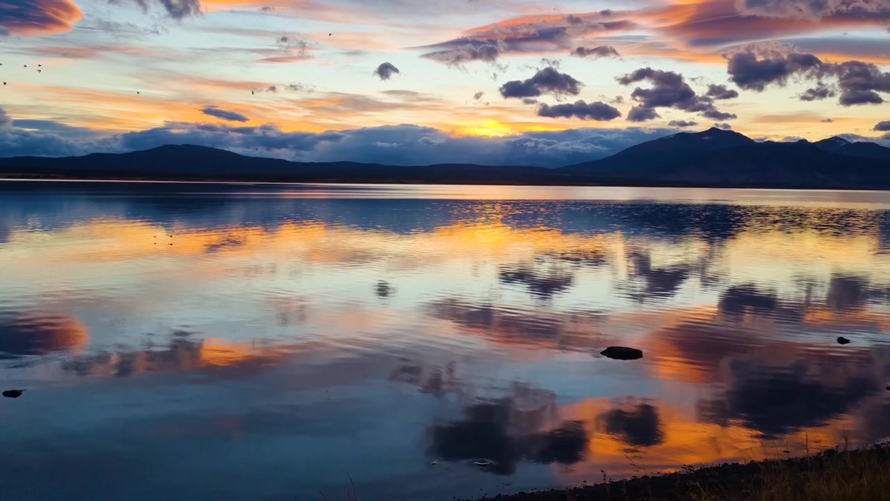 Ohromující západ slunce nad zálivem Última Esperanza poblíž Puerto Natales v Chile. Zlaté a červené mraky se odrážejí na klidných vodách a vytvářejí poklidnou večerní scénu v dramatické patagonské krajině.