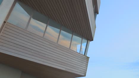 Angular-building-with-cloud-reflections-in-windows-during-sunset-in-slow-motion-at-Fleetwood,-Lancashire,-UK