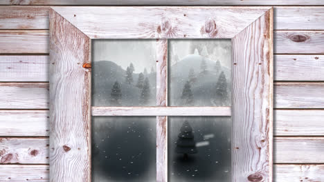 wooden window frame against snow falling over multiple trees on winter landscape