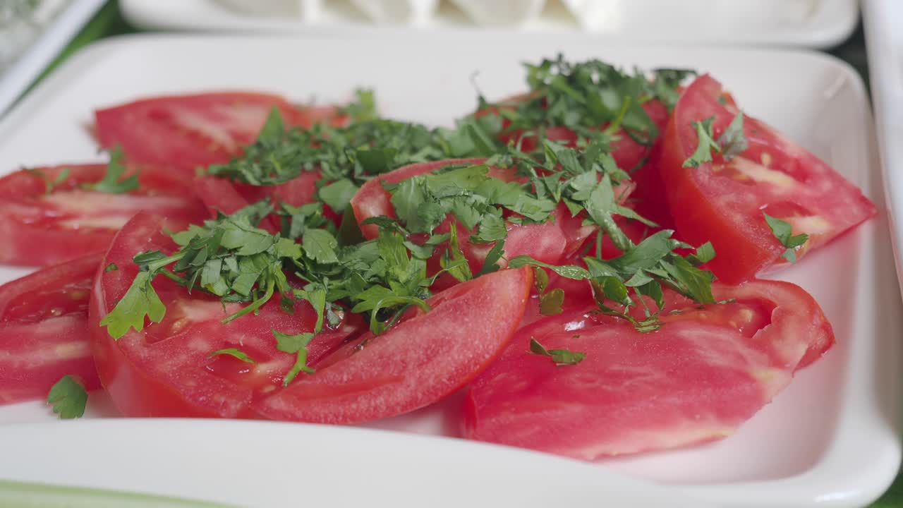 primer plano de tomates rojos cortados con perejil picado en un plato blanco