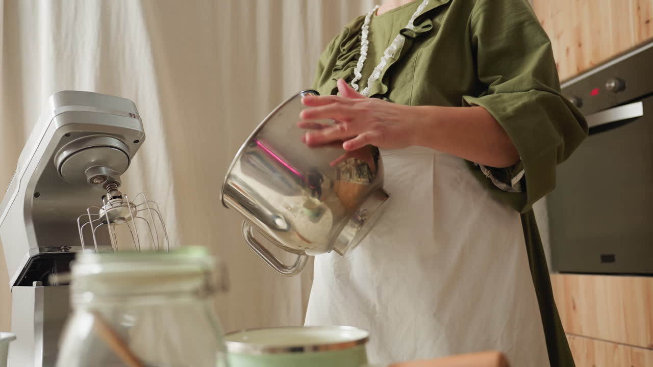 Cook beating stainless bowl while dancing playfully in cozy kitchen with bowl reflecting hand movements and surrounding background elements