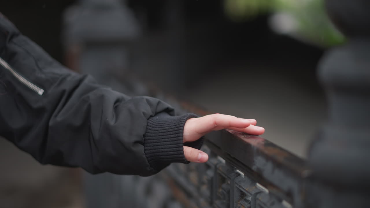 Rainy reflective stroll. Thoughtful walk through rainy scene. Serene walk along rainslicked railing amidst city silence. Contemplative journey beside raincovered railings in quiet urban surroundings