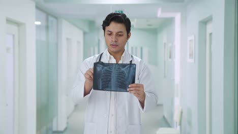 serio médico indio comprobando el informe de rayos x