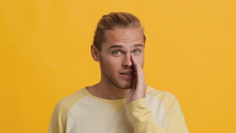 man whispering on yellow background