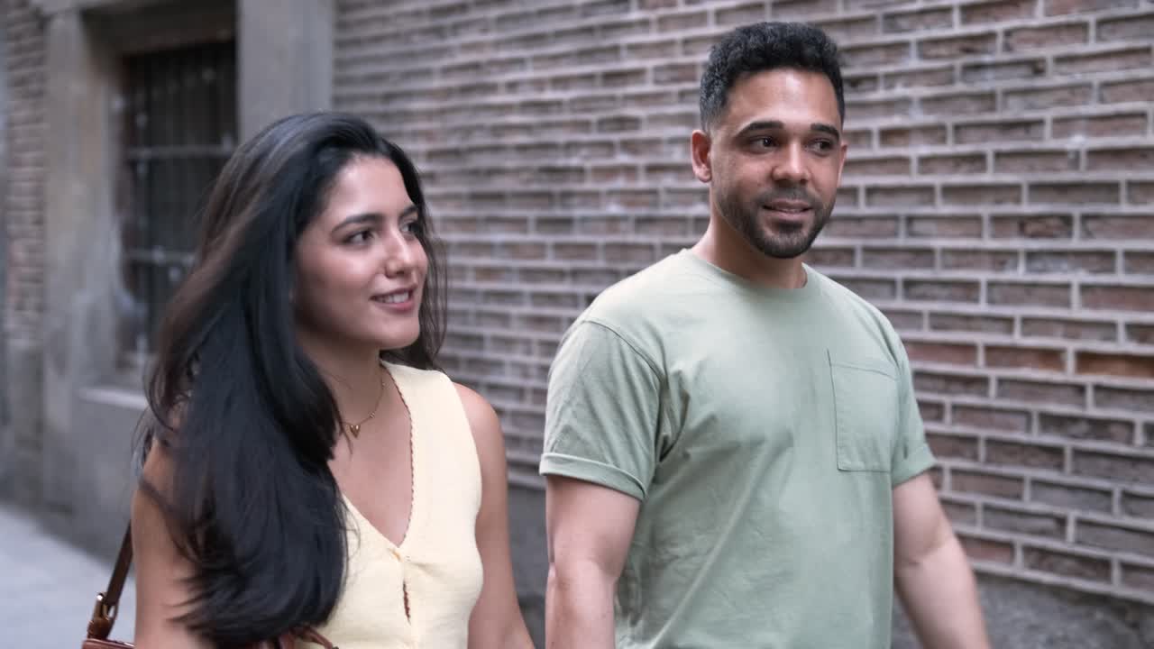 Couple talking as they walking on sidewalk in city during daytime