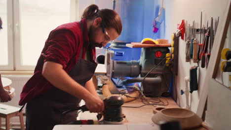 team in woodworking shop using angle grinder to create wooden decorations