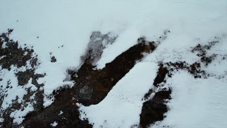 Aerial-birdseye-view-of-a-hiker-on-the-peak-of-a-snow-covered-mountain-ascending-pedestal-shot