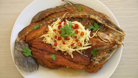 lubina frita con salsa de pescado y ensalada picante en el plato
