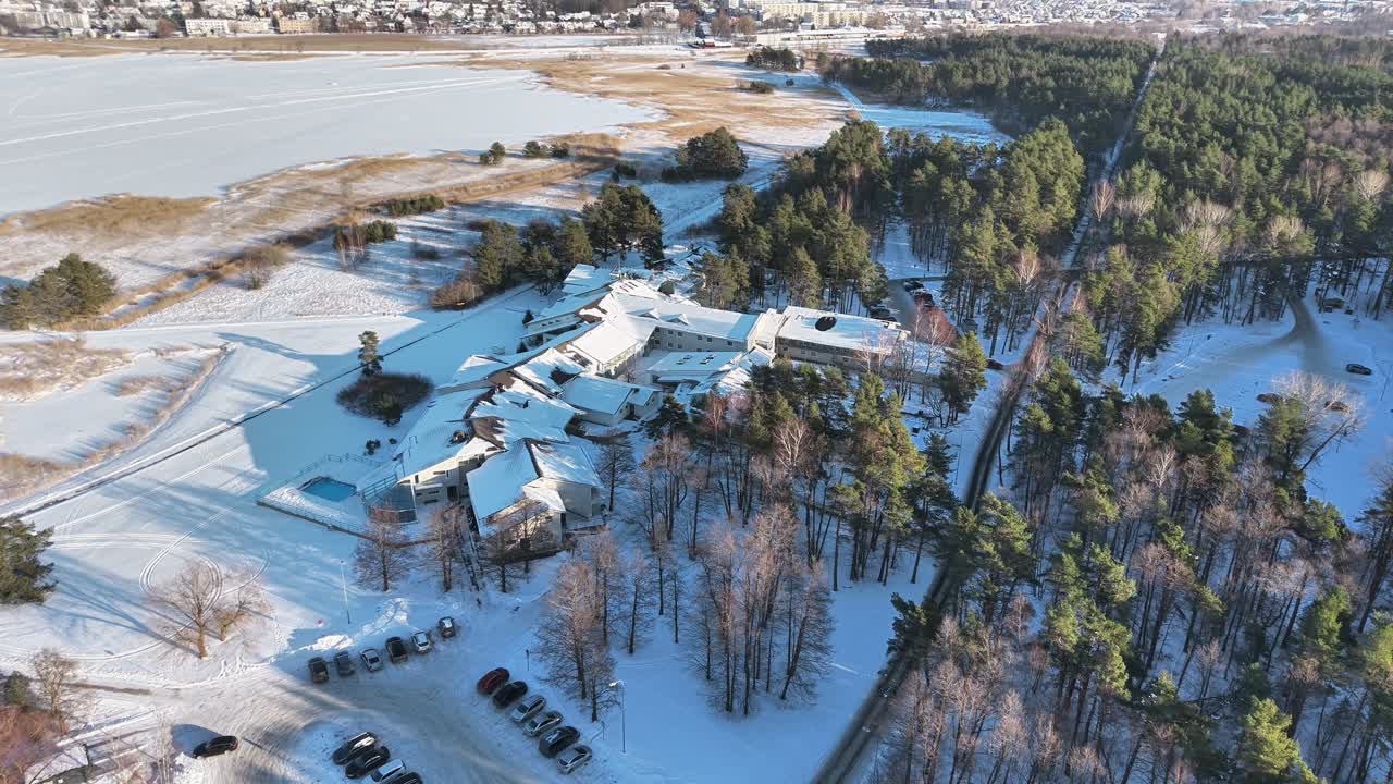 Lumen peittämä metsä ja rakennukset jäätyneen järven lähellä, Haapsalun kaupunki Virossa.
