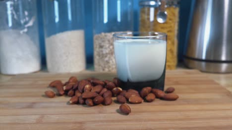 vaso de leche de almendras y almendras que se acercan para enfocarse en un mostrador de cocina