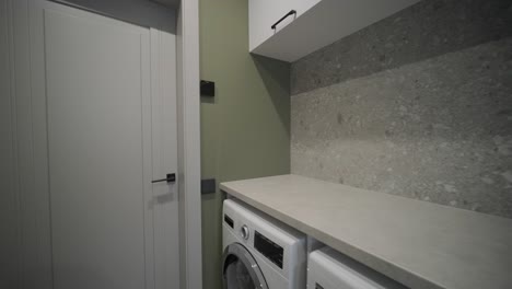 a functional laundry room with modern appliances, stone countertops, a deep black sink, and a heated towel rail for added convenience