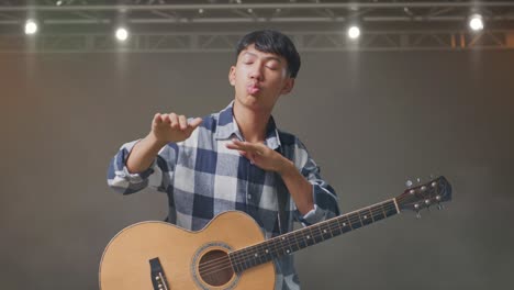 adolescente asiático con baile de guitarra en el escenario