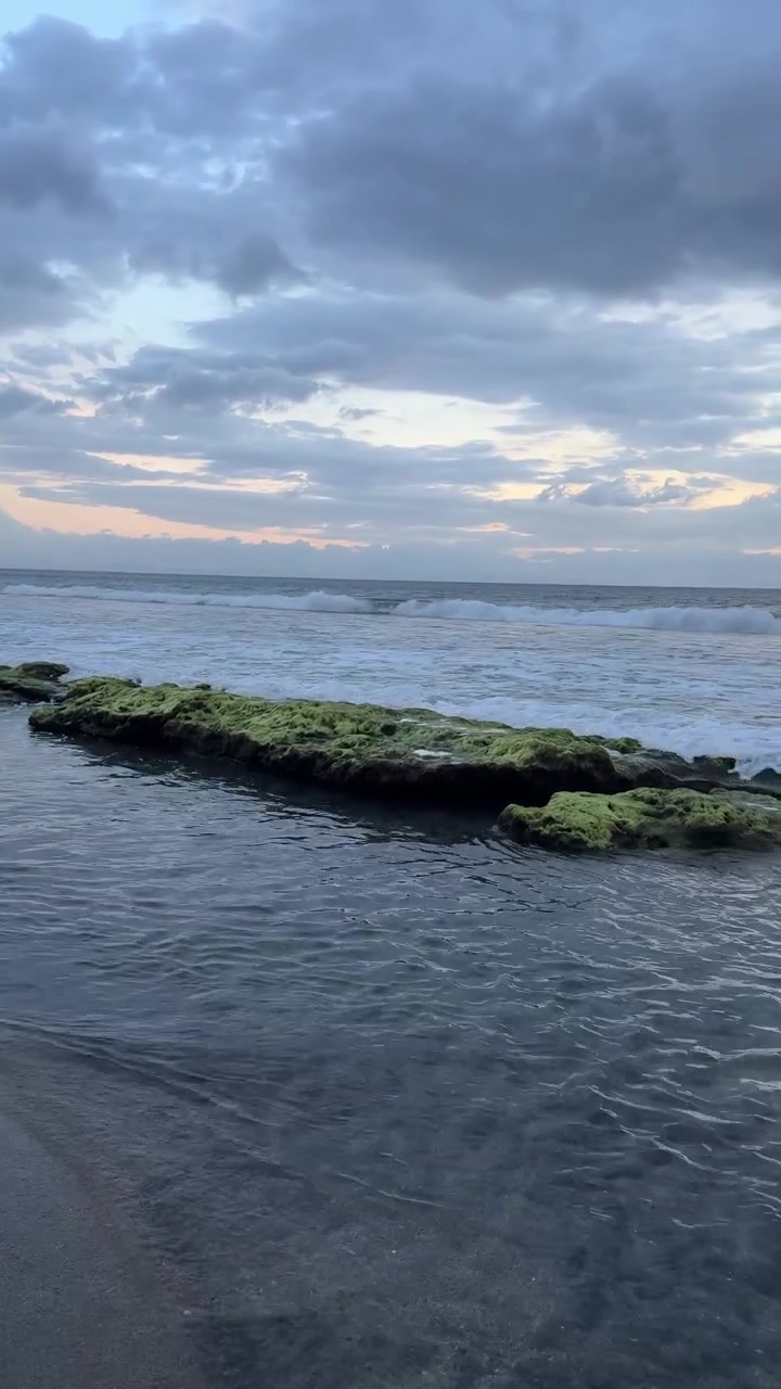 Onde oceaniche serene e rocce coperte di muschio sotto un cielo nuvoloso