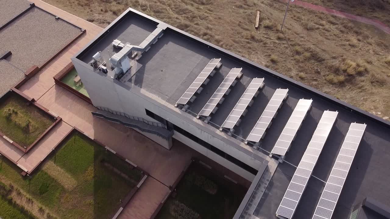 An aerial view of a modern rooftop. It shows the installation of photovoltaic solar panels along with ventilation ducts and HVAC units