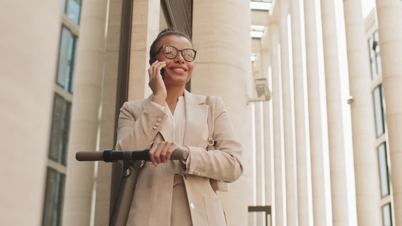 Modern Businesswoman with Kick Scooter Talking on Phone Outdoors