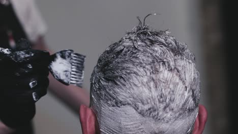 peluquero tiñendo el cabello de un cliente con un cepillo