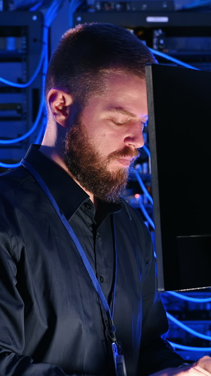 Man programming in a server room. Vertical