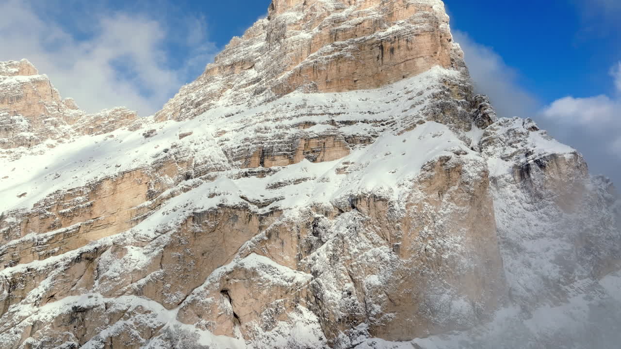 Aerial drone view of snow on the Sassongher mountain in the Dolomites, Italy with the blue sky on the background