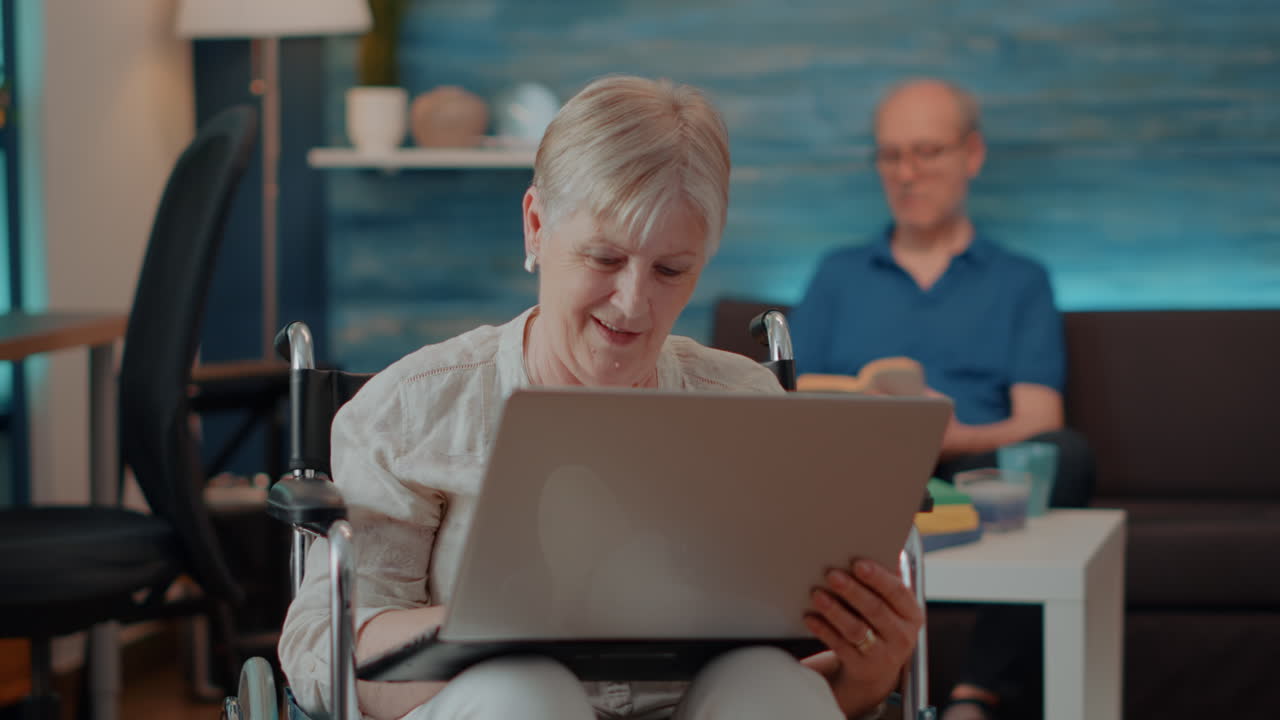 Senior Woman Using Laptop in Wheelchair at Home
