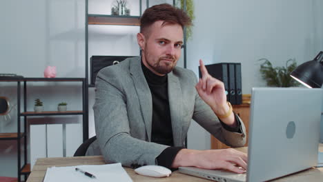 business man working on laptop shakes finger, saying no, be careful, giving advice to avoid mistake